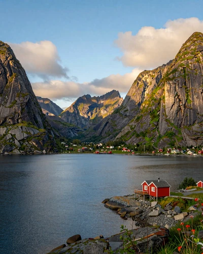 Scenic Norwegian fjord with dramatic mountain cliffs and a traditional red cabin on the shore at golden hour